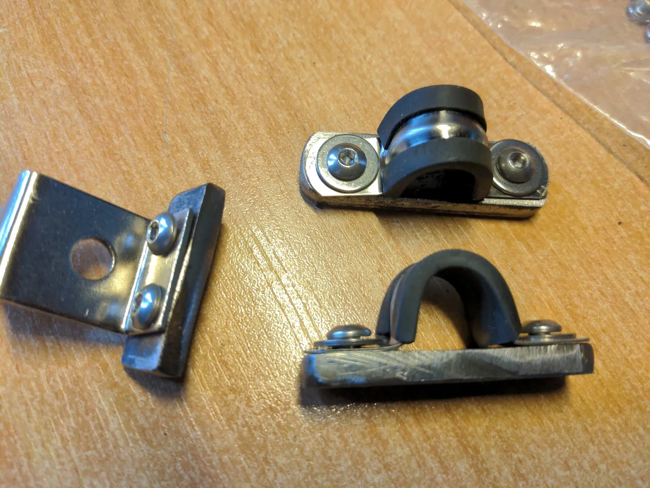 Some pieces of steel, about 5mm thick. Two of them have omega-shaped hose clamps bolted into them, and the other has a small stainless steel metal bracket attached to it.