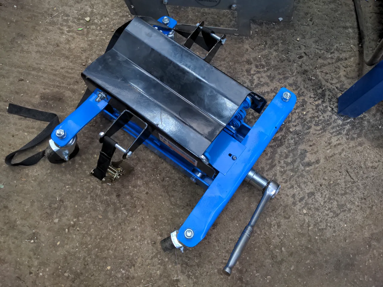 A Draper gearbox jack. It has four wheels. It has a large flat centre section where it lifts. A half-inch-drive ratchet is attached which rotates the mechanism.