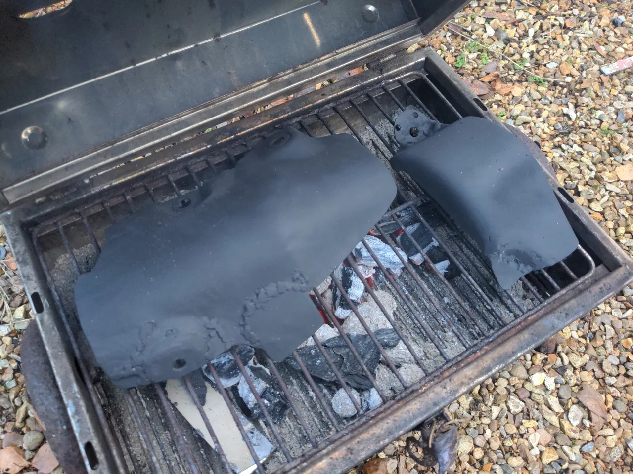 Both parts of my heatshield painted black and sitting on a hot BBQ.