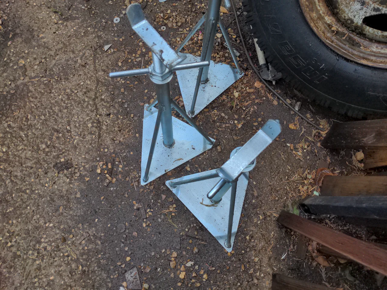 Some galvanised steel caravan stands. They have a flat triangular base, from which three steel rods go upwards. At the top is a screw-adjustable section to change the height, with a cup for something about the size of a chassis rail to sit in.