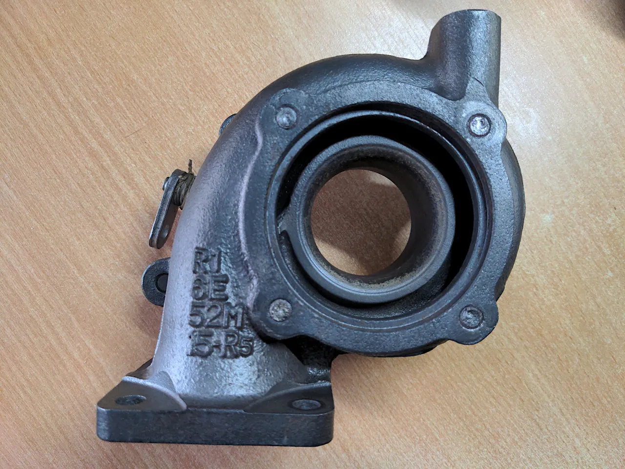 An IHI VJ9 turbo stripped down to its turbine housing - it is about a third of its full size with everything else removed. The remnants of four sheared bolts are visible.