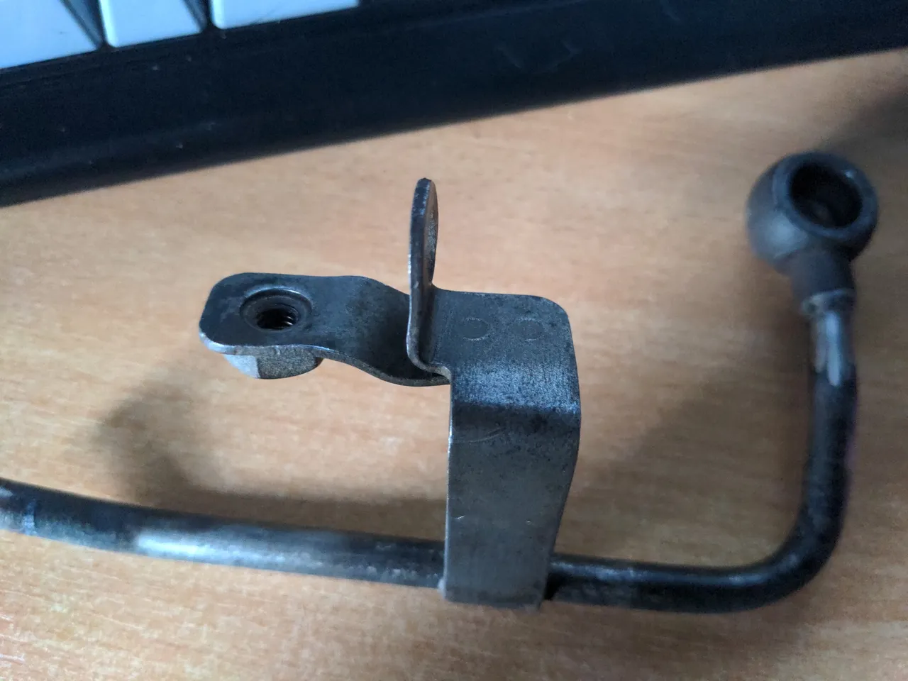 A nickel-steel water pipe, with a steel bracket soldered on to it - this is the factory bracket. On the other end of the bracket is an M6 threaded hole.