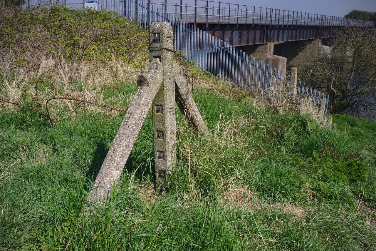 An old railway fence post, with the Magdalen railway bridge just about visible in the background.