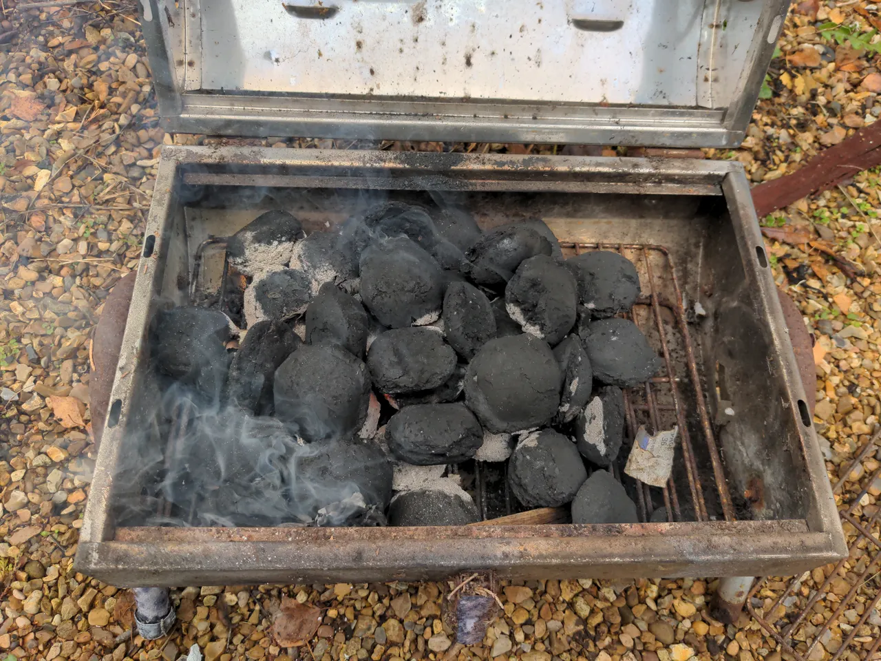 A small barbecue, with some charcoal that has started to turn grey.