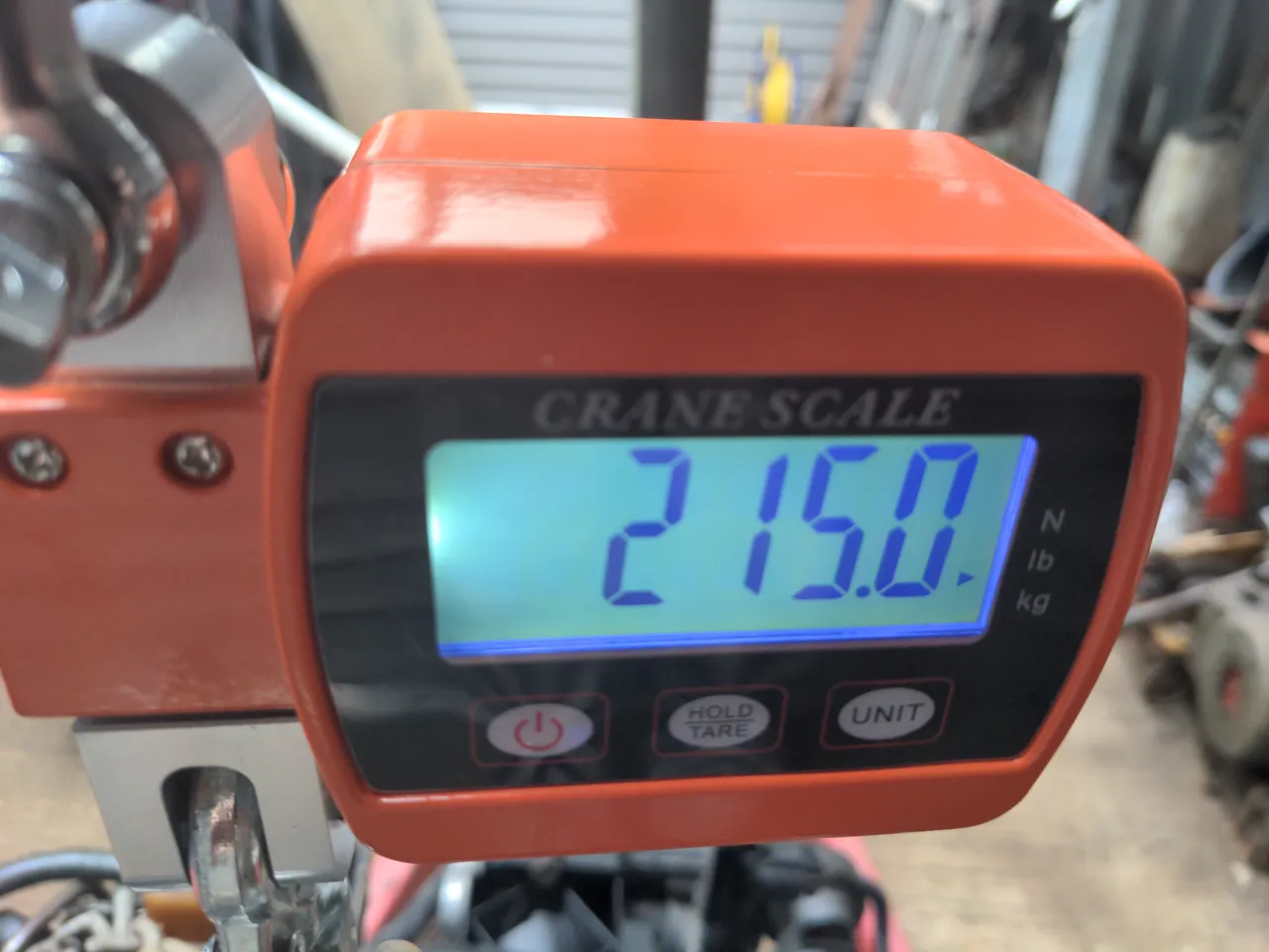 A crane scale showing a weight of 215 kilos. This is the weight of a GM LS1 engine.
