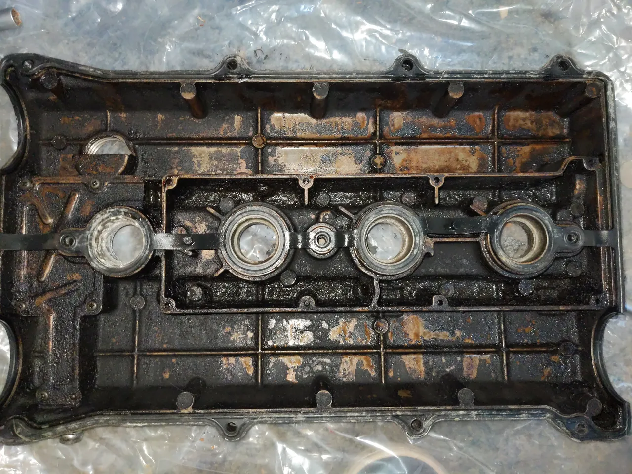 The underside of my B6T rocker cover, with blackened oil baked on so hard that it has hardened.
