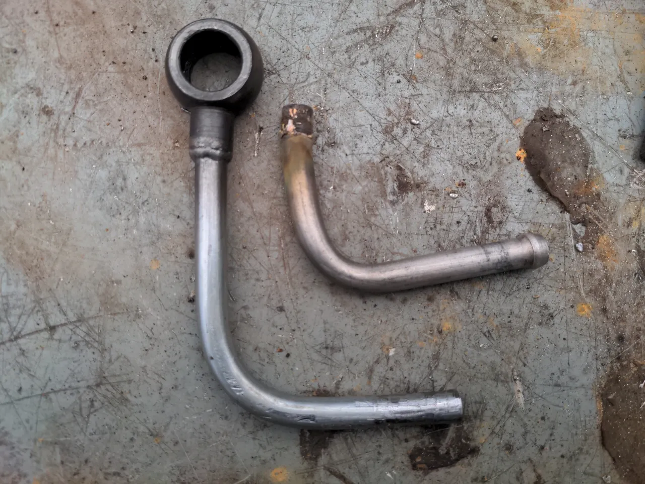 The water drain pipe is a 90 degree nickel-steel pipe, with a banjo bolt at one end. Here, the old one is shown next to the new one. The new one is about an inch or so longer on one of its lengths.