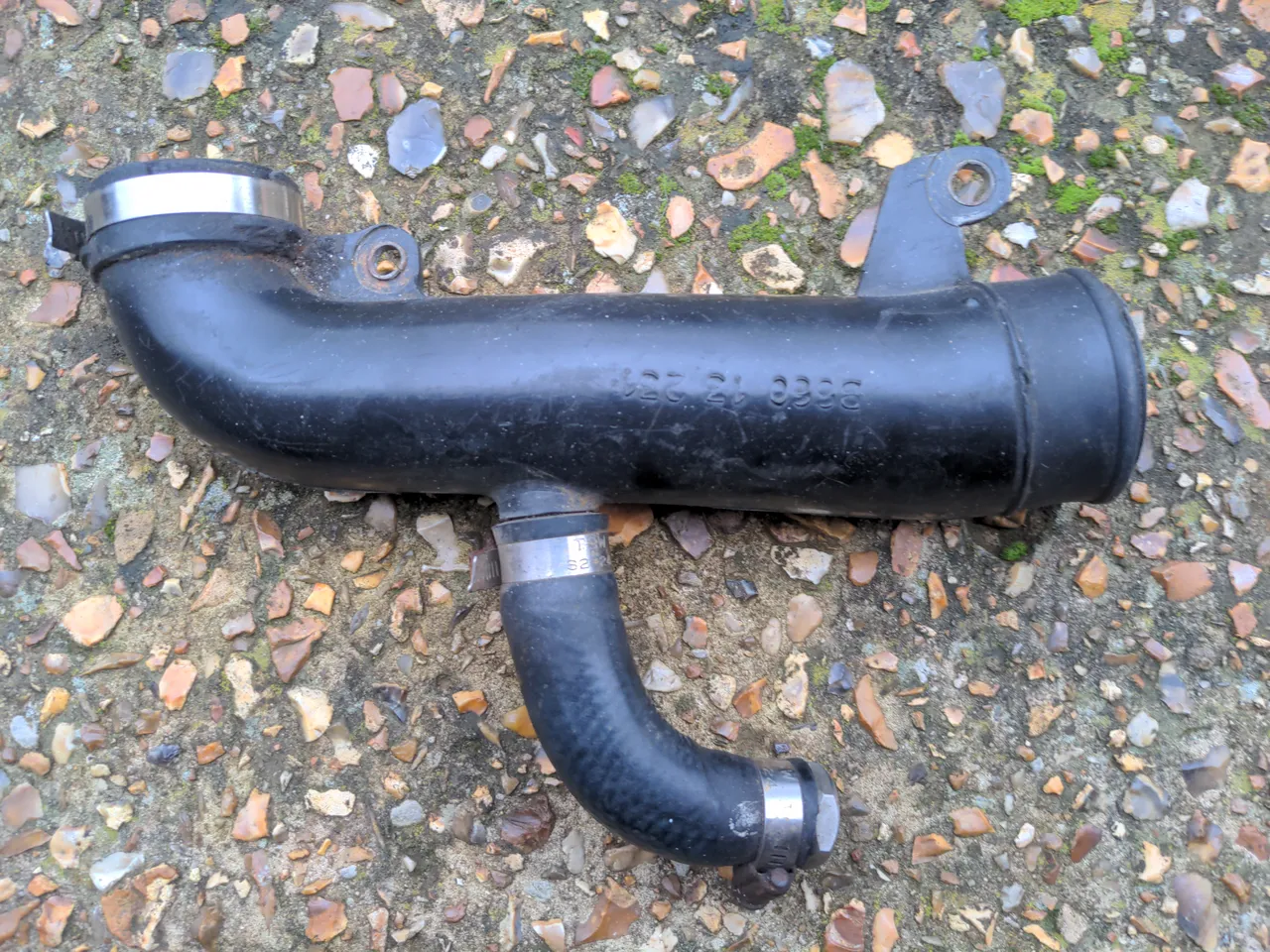 A plastic intake pipe. It is bent through 90 degrees about an inch into its length. It has a stub pipe that has been blanked off about half way up its length.