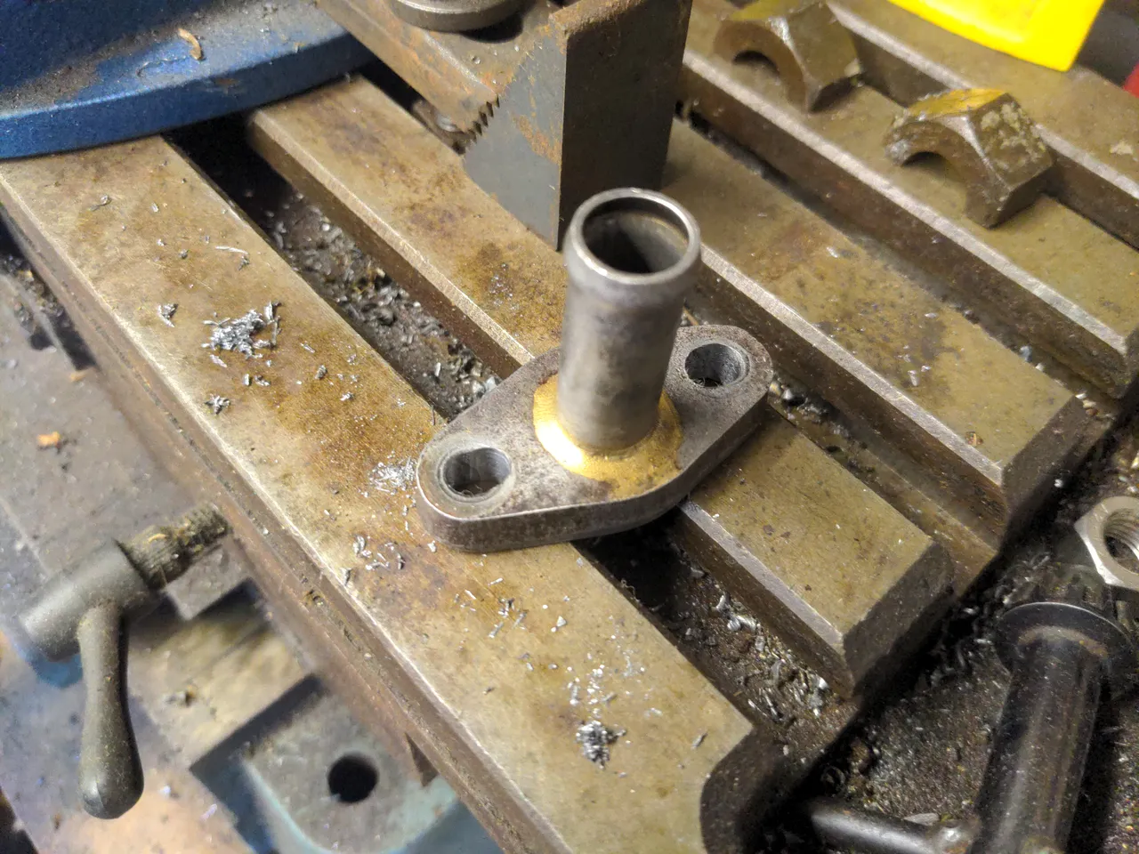 An oil drain, which is a roughly 8mm thick piece of steel with two bolt holes spaced 40mm apart, and a pipe sticking out at a 90 degree angle. The two holes have been slotted to permit them to fit to bolt holes that are 38mm apart.