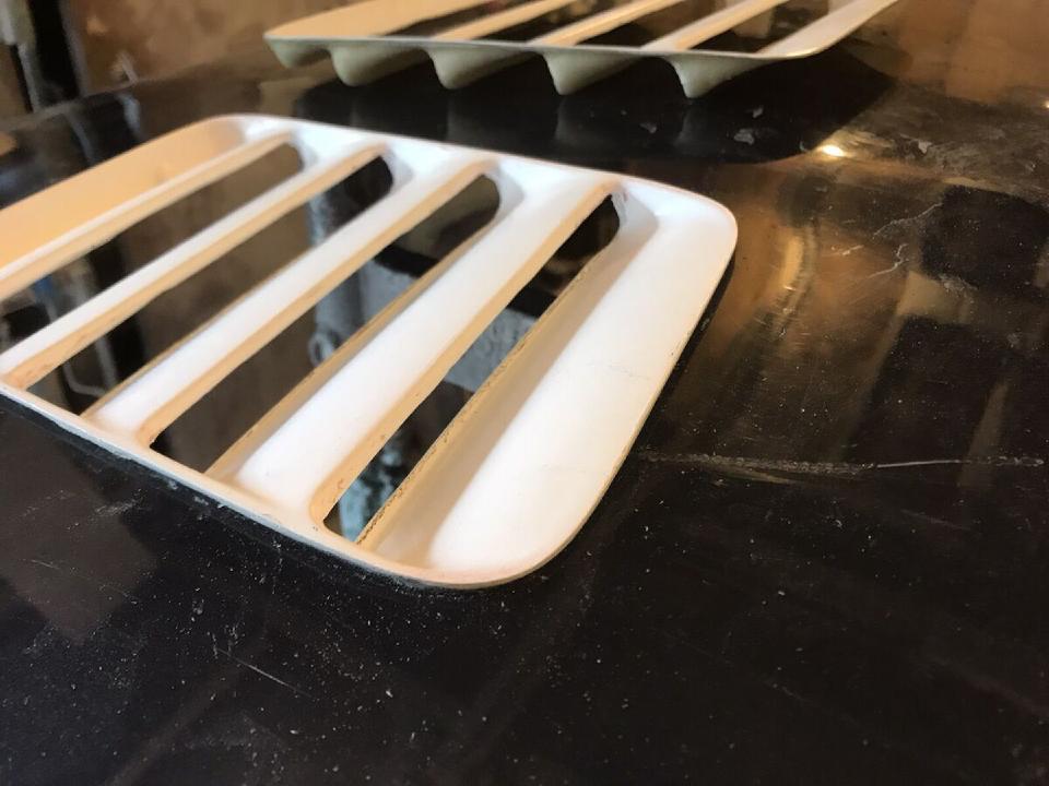 A pair of white fibreglass Ford RS500 bonnet vents sitting on a black background.