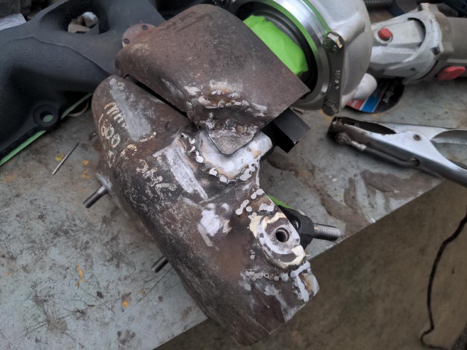 My heat shield sitting on a workbench of sorts. There are some crude welds on both sections.