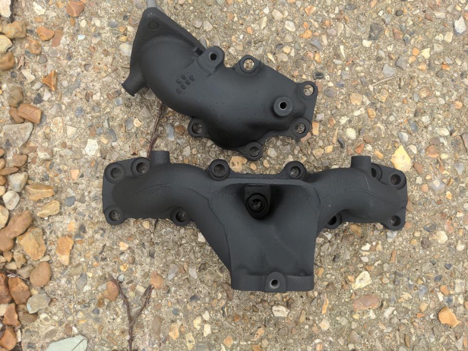 A cast-iron exhaust manifold and downpipe, both in matt black ceramic coating.