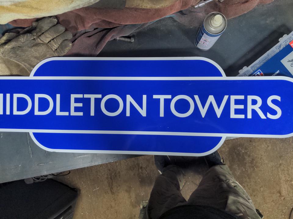 A reproduction sign for Middleton Towers railway station in the 'hot dog' style of the 1950s - it is blue with Gill Sans text.