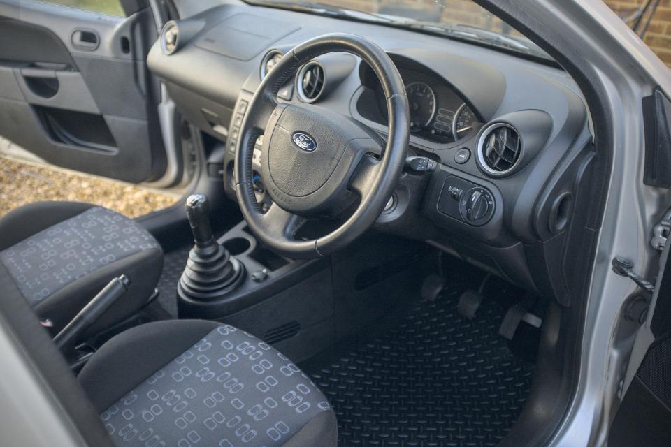 The interior of a fifth-generation Ford Fiesta, fitted with aftermarket rubber floor mats.