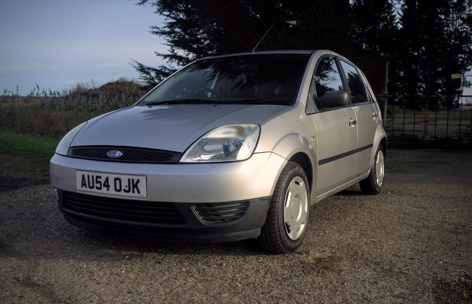 A silver fifth-generation Ford Fiesta, with some minor battle scars.