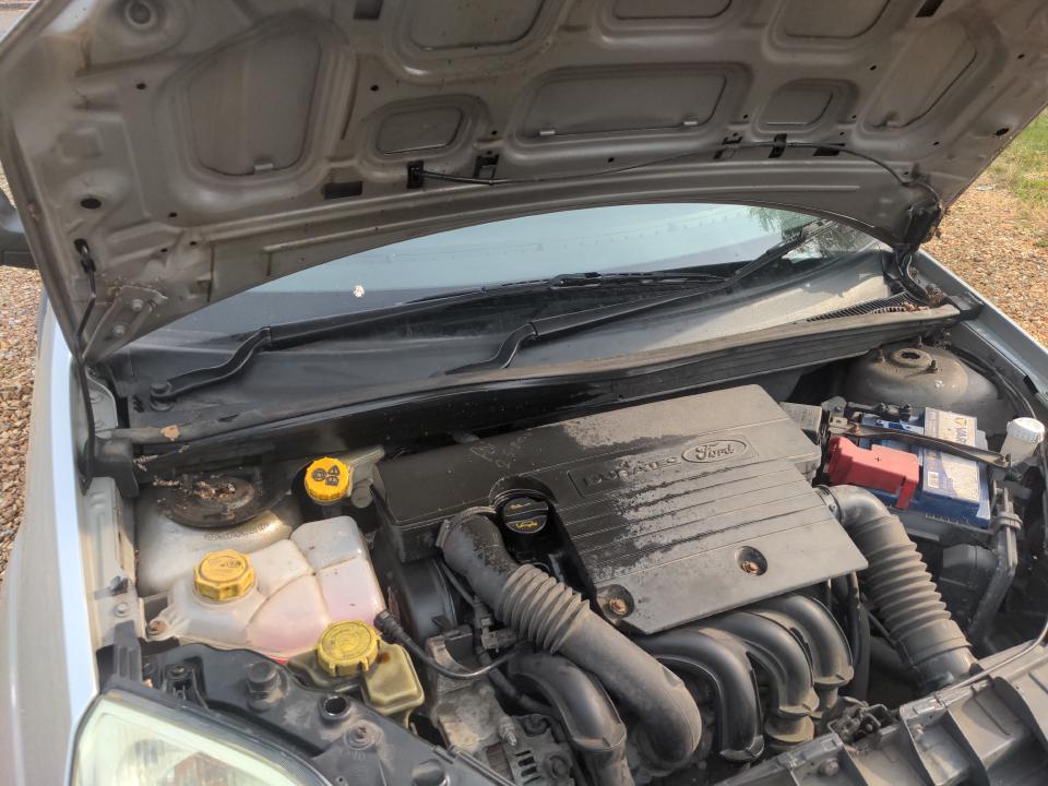 The mess under the bonnet after my oil filler cap came off. The plastic cover of the engine is conspicuously black compared to the rest.