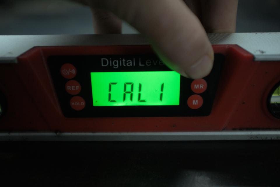 My digital level reading CAL1 on its backlit green LCD display, indicating the first reference measurement for calibration has been taken.