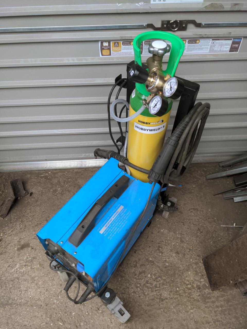 The finished cart in its entirety; the welder is in place, the gas bottle is behind it, and there is extra tubing. Cables are neatly wrapped around protrusions on the "pram handle".