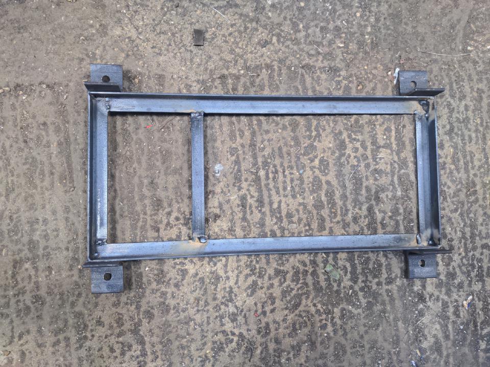 The frame for my welding cart, which is five pieces of angle iron; four forming a rectangle and one reinforcing crossmember. It has four identical pieces of the previously-mentioned angle iron welded on to each corner on the long sides.