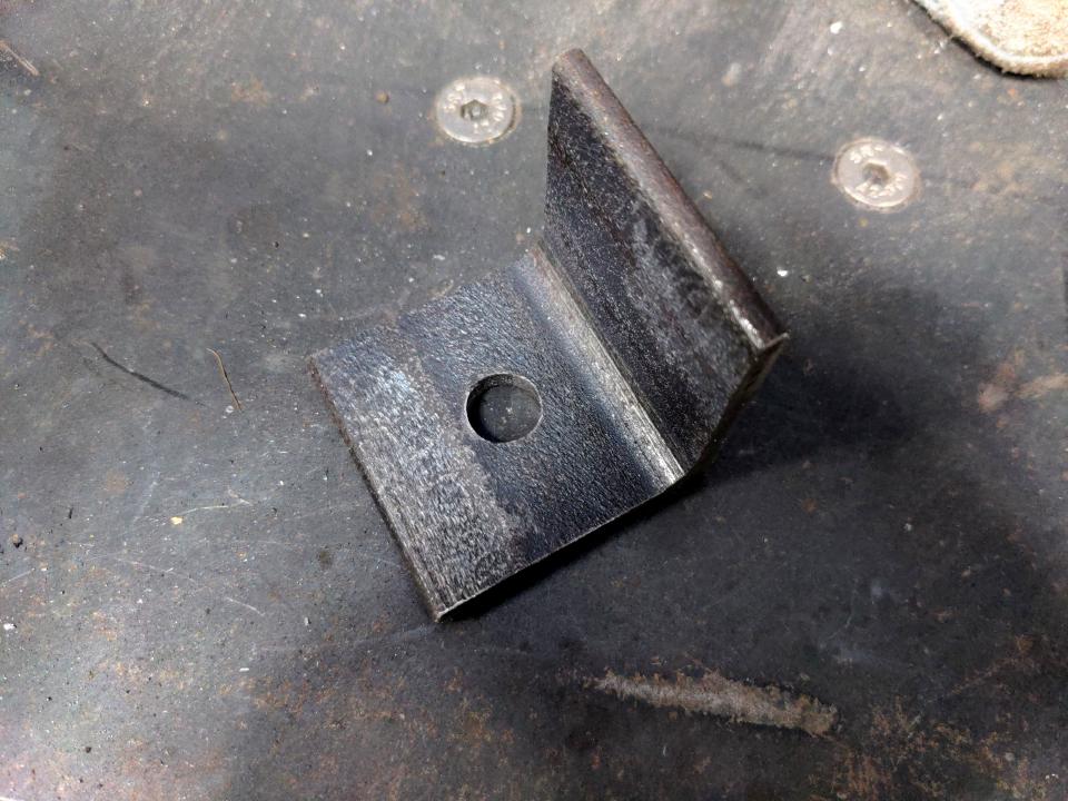 A 50mm-long offcut of 50mmx6mm angle iron. A 12mm hole has been drilled in the center of one of the sides.