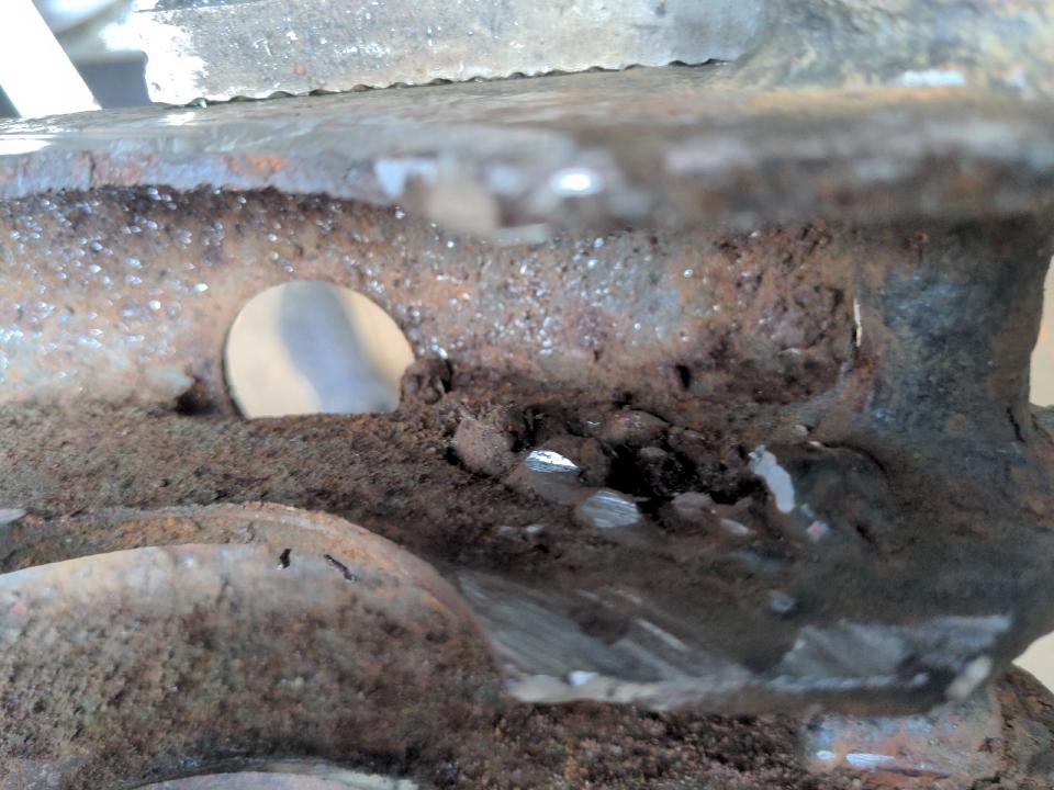 A suspiciously-blobby repair on some rusted steel; the repair itself has gained plenty of rust too.