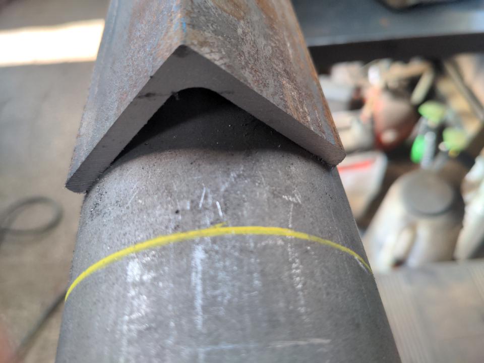 A piece of angle iron, sitting along its length on top of a piece of steel tube.