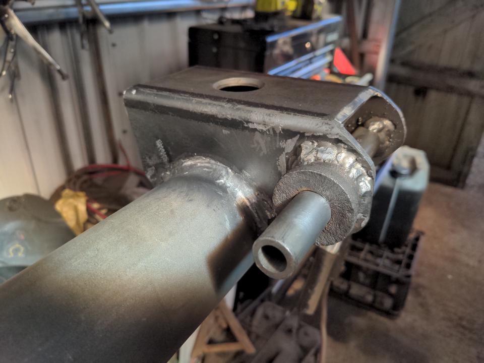 One spring perch fully welded on; excess on the welds has been ground down, leaving a smooth transition.