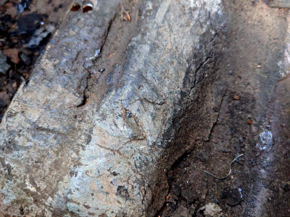 A view of the boot floor of my Rover P5. It is covered in a very thick black paint-like substance. It has a coarse-textured surface.