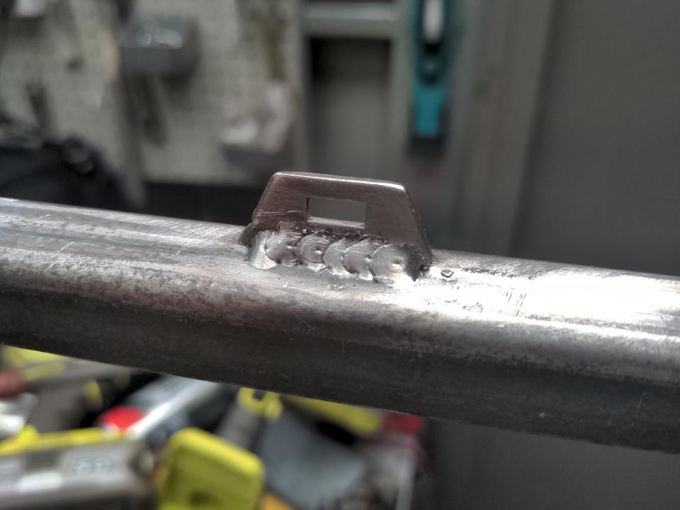 A cable tie attachment points welded on to the mounting frame for my radiator. They are a trapezoid shape about 25mm long and 15mm tall, made out of ~2mm steel. In the middle of this shape is a rectangle; a cable (zip) tie goes through this and gives a point to hold a wiring harness to.