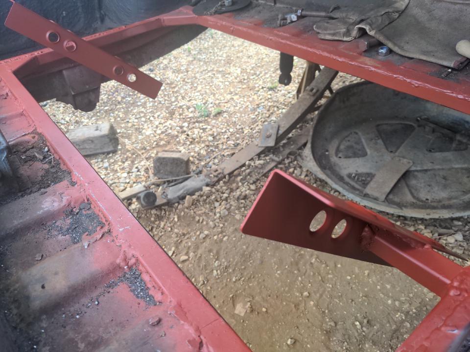 The brackets for my rear-mount radiator welded into the space cut into the boot floor of my P5. They are sprayed in red anti-rust primer..