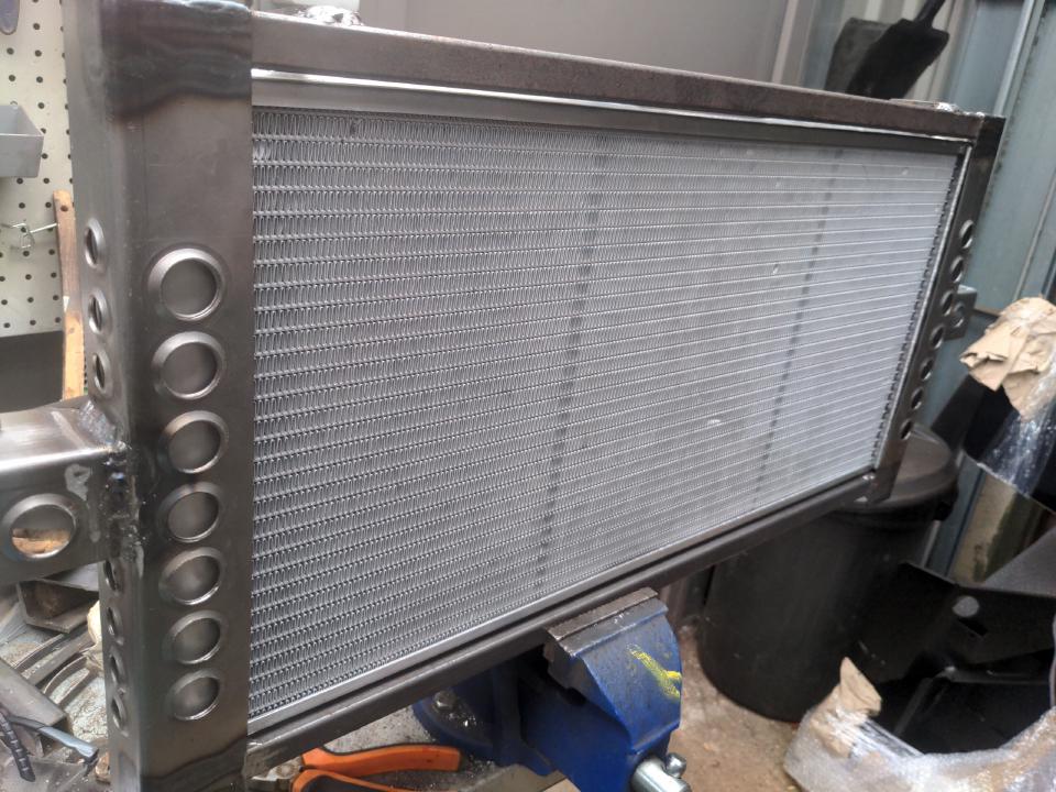 A mounting frame for a Sierra Cosworth radiator (with the intent of putting it into something that is definitely not a Sierra Cosworth). On the left and right side are some 50mm pieces of angle iron, 2mm thick, each with 14 dimple dies (!). Across the top and bottom are lengths of 20mm box section steel.