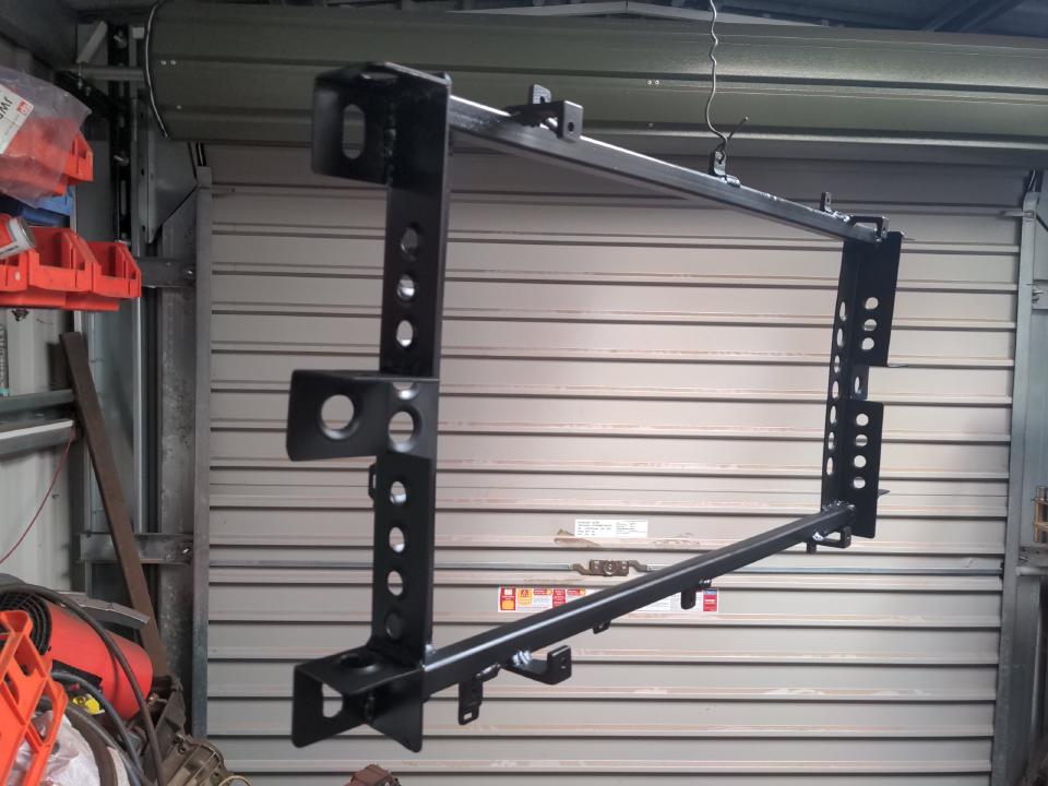 The frame for my radiator hanging from the ceiling by some wire, painted in stain black paint.