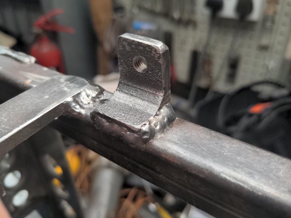 An offcut of angle iron with some M6-threaded holes drilled and tapped into it, welded onto my radiator mounting frame.