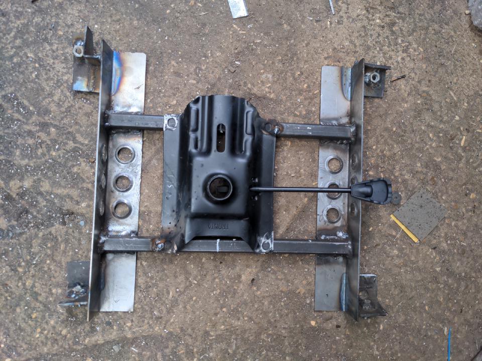 The subframe in the previous photo, but this time four mounting points have been welded on with captive nuts (for two of them) or captive bolts (the other two). Not quite in the middle, the base plate for a swivel chair (the plate part that goes on top of the gas ram and contains the lever to control it) has been tacked on.