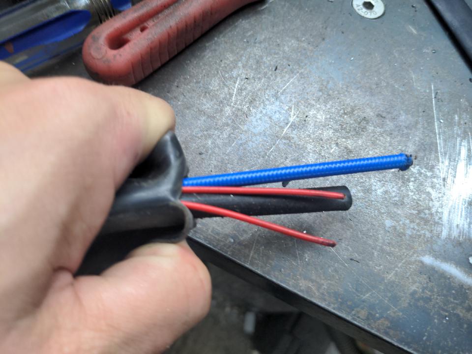 Peeling open the outer cover of a cheap MIG torch, we see two small wires, one thick wire, and one wire feed guide.