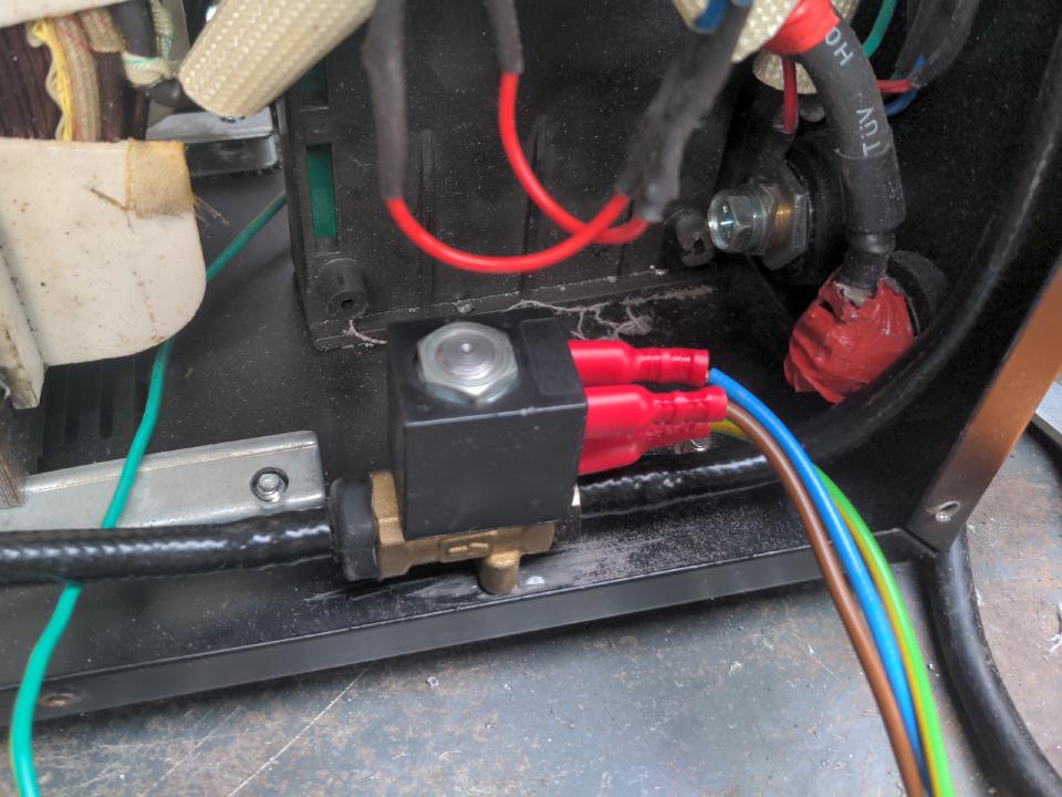 A small AC powered solenoid screwed in to the base plate of the welder.