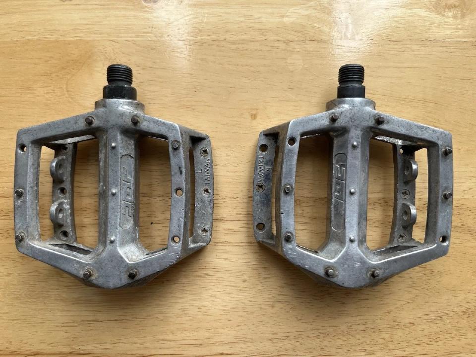 Some DMR pedals. They are of the flat "DX" style. They have a mild coating of aluminium corrosion and need a good clean. Several of the studs are missing.