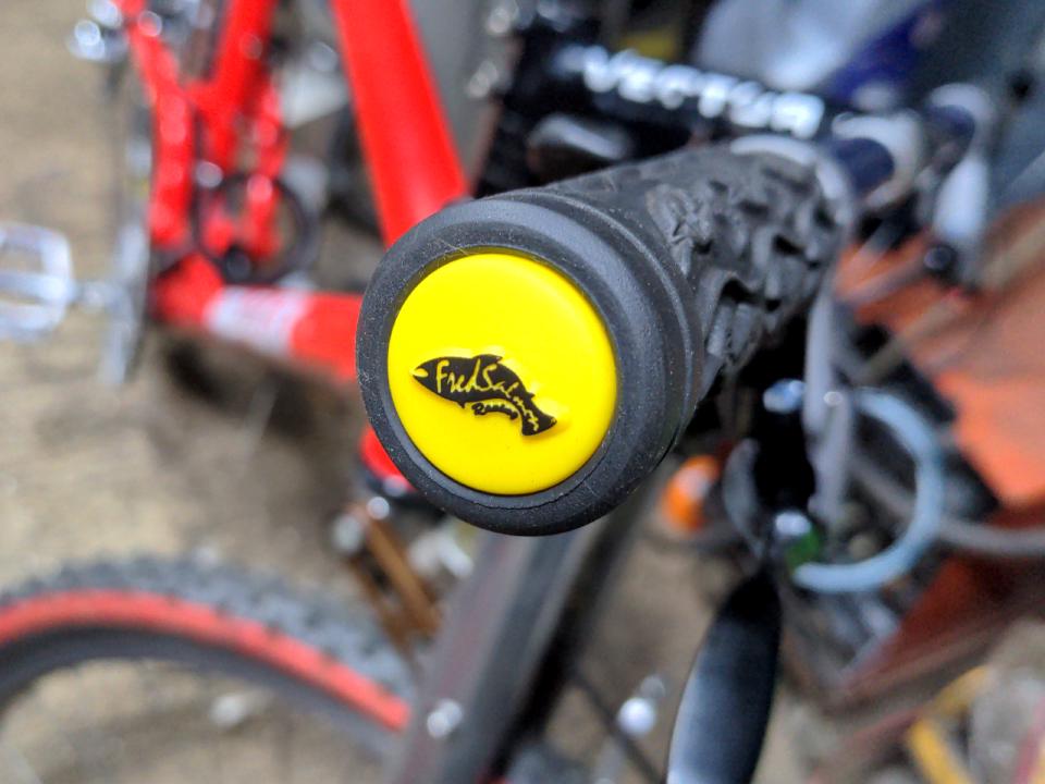 Some Fred Salmon bar ends. They are yellow, and they have a black fish design on them.
