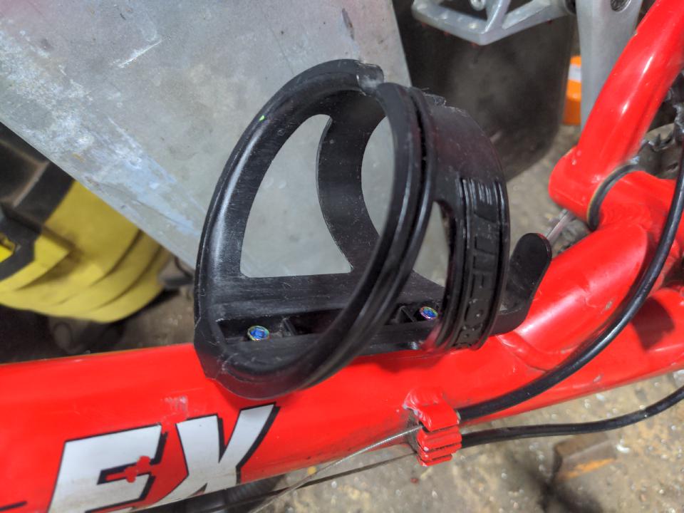 The new bottle cage; it is shiny black plastic and has rainbow-anodised bolts just about visible.