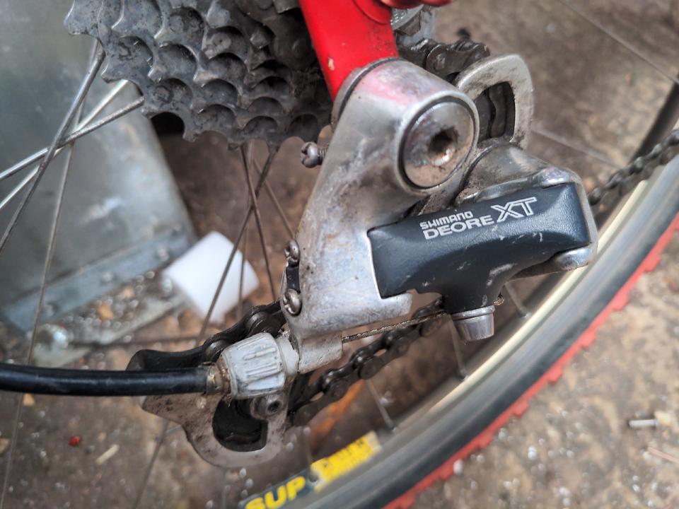 The original rear mech fitted to the bike; it is from the 1990s and is silver with a black main arm.