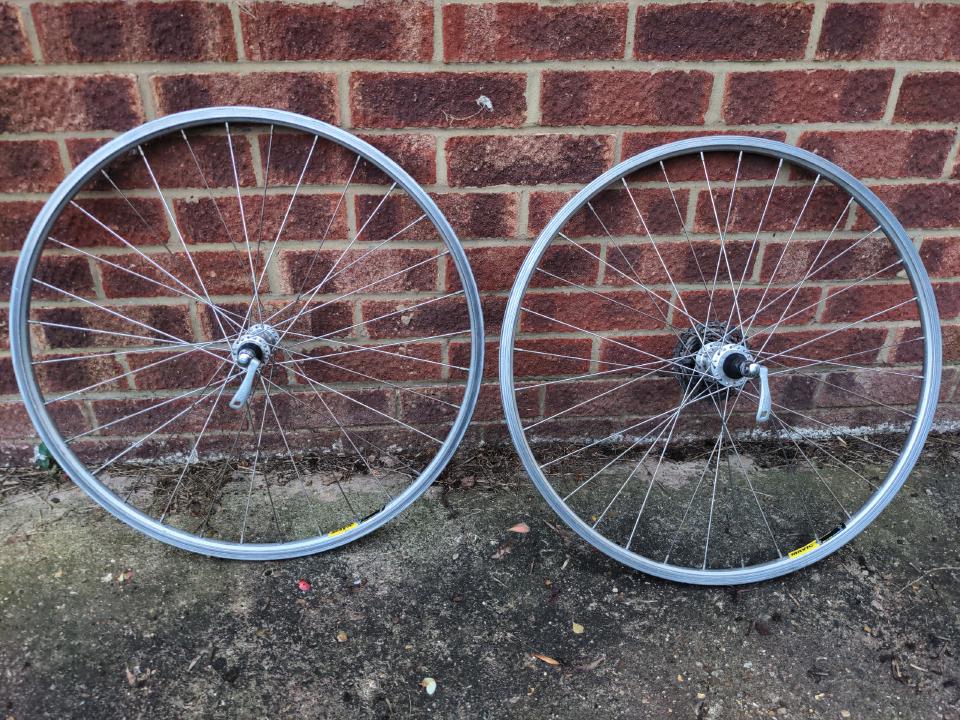 A pair of bicycle wheels leaning against a brick wall.
