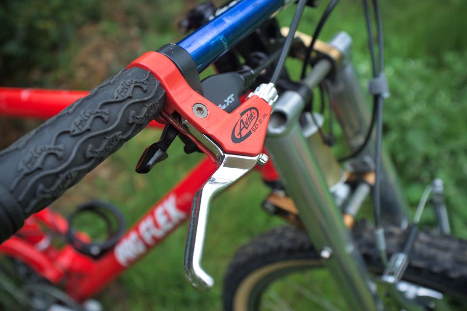 An Avid Speed Dial 2.0L brake lever. It has a red body and a silver lever.