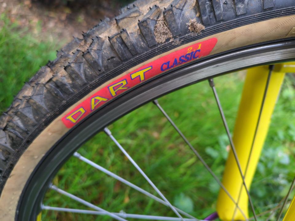 Closeup of the "DART" lettering on an amber-walled Dart Classic tyre; the text is blue and yellow on red.