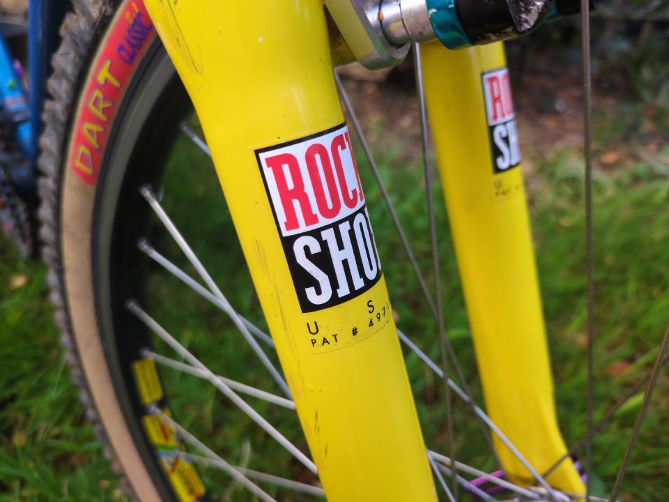 Closeup of the ROCK SHOX stickers on some yellow Judy SL suspension forks.