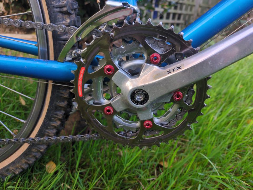 My STX chainset. The arms are silver and the outer chainring is a reddish-silver colour. I have replaced the five visible chainring bolts with red ones.