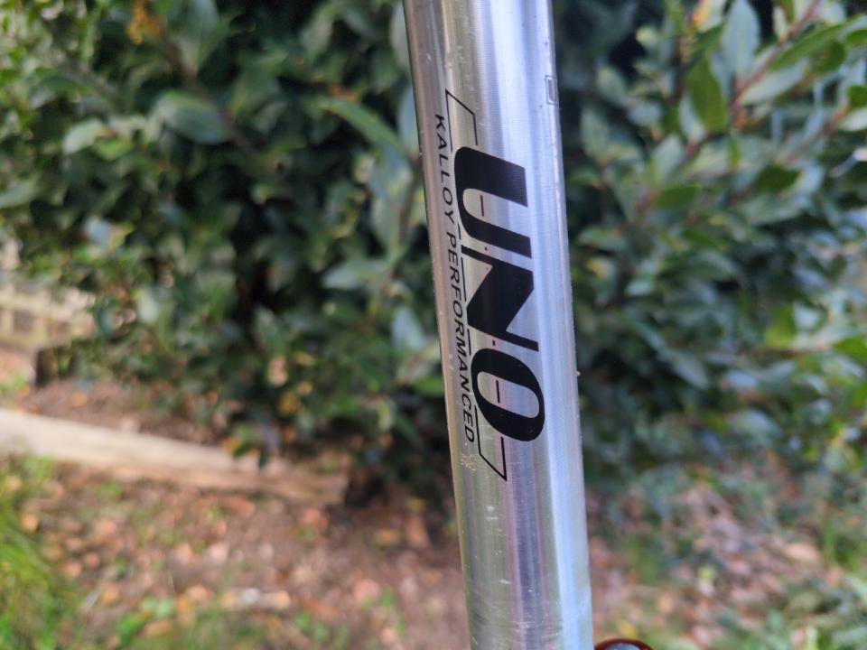 A plain silver seatpost on a bike; unblingy and unadorned other than the "UNO" brand writing