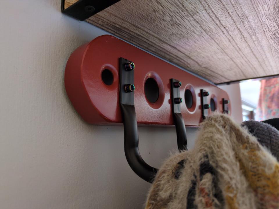 The finished rail; as the previous picture, but now painted red, with four heavy-duty black coat hooks added.