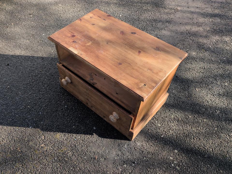 A two-drawer chest of draws, with one drawer missing. It is made of solid, light-coloured wood.