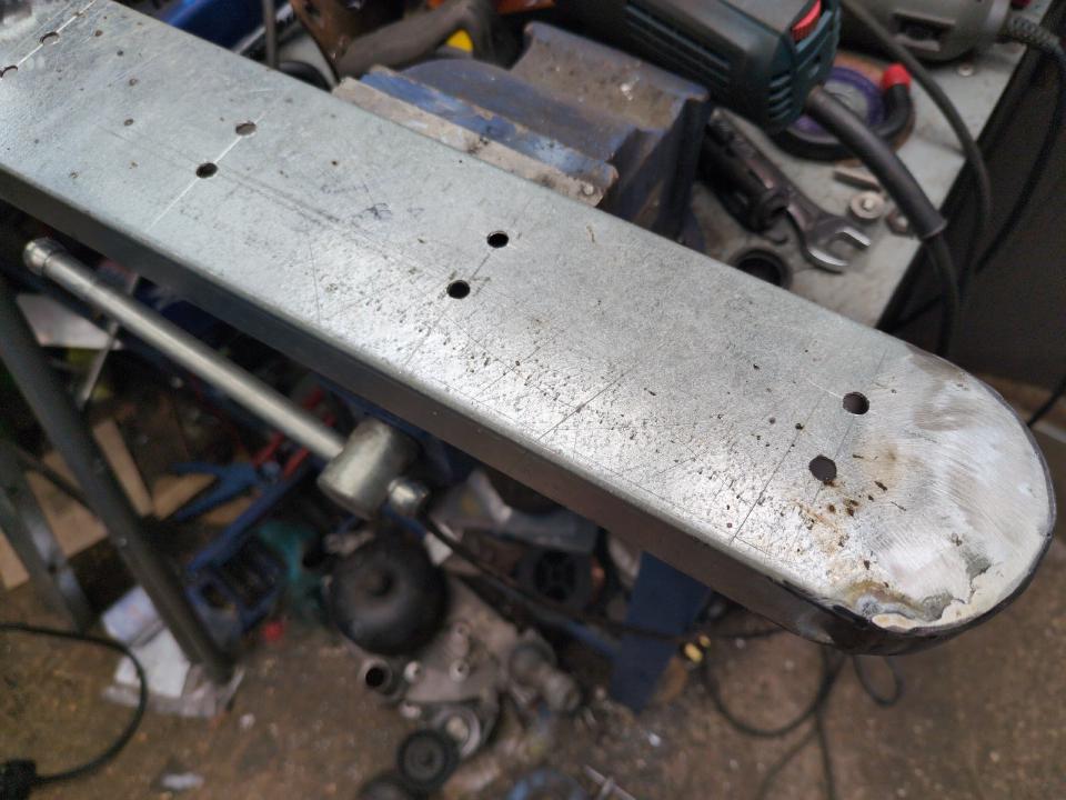 That random piece of steel, but now with curves cut into the sides, returns added to the curves, and with 8 small holes drilled for attaching coat hooks.