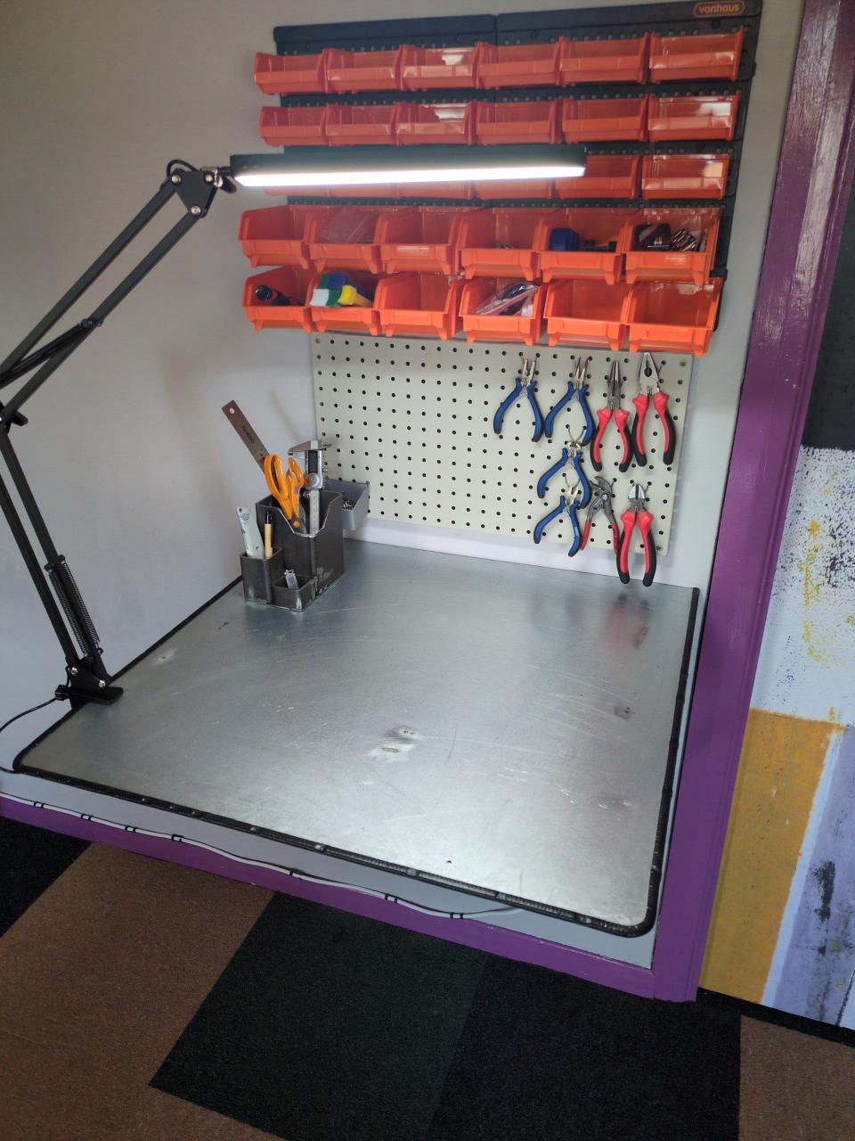 A finished view of my workbench, with 700x700mm work top, over-engineered angle brackets holding it to the wall, a full pen pot, and an LED lamp.